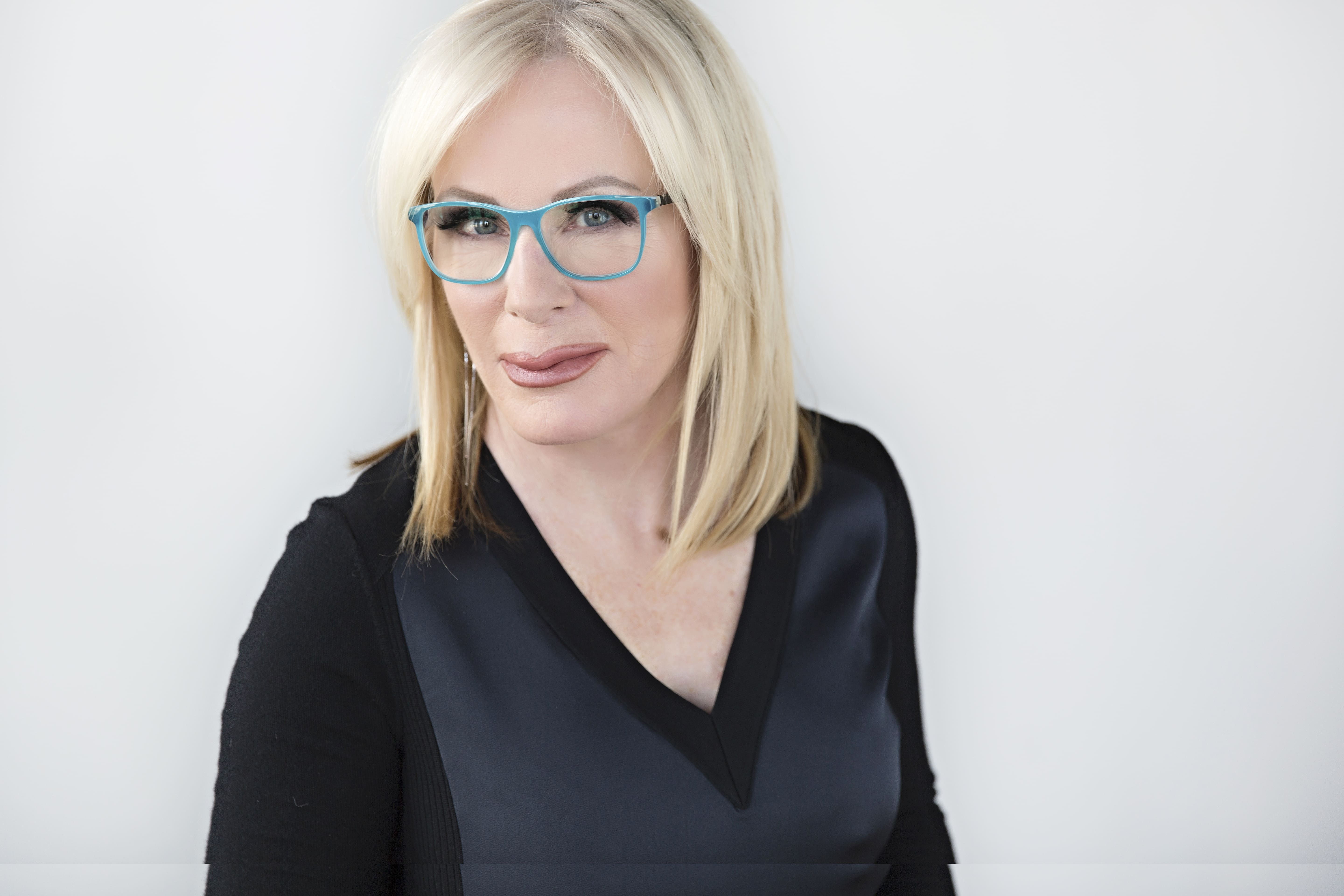 Headshot of Blonde female wearing turquoise plastic designer frame Maple Grove Eye Doctors at Pearle Vision