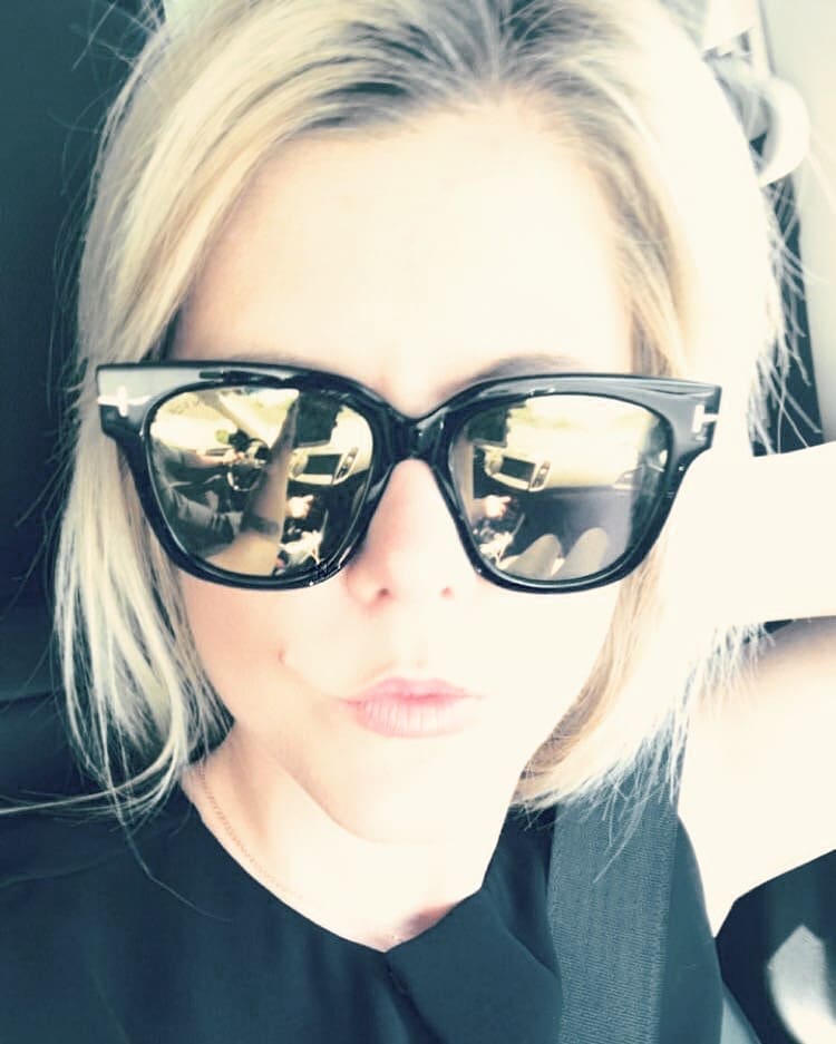 Blonde female wearing large Dior black plastic sunglasses with mirrored lenses Maple Grove Eye Doctors at Pearle Vision