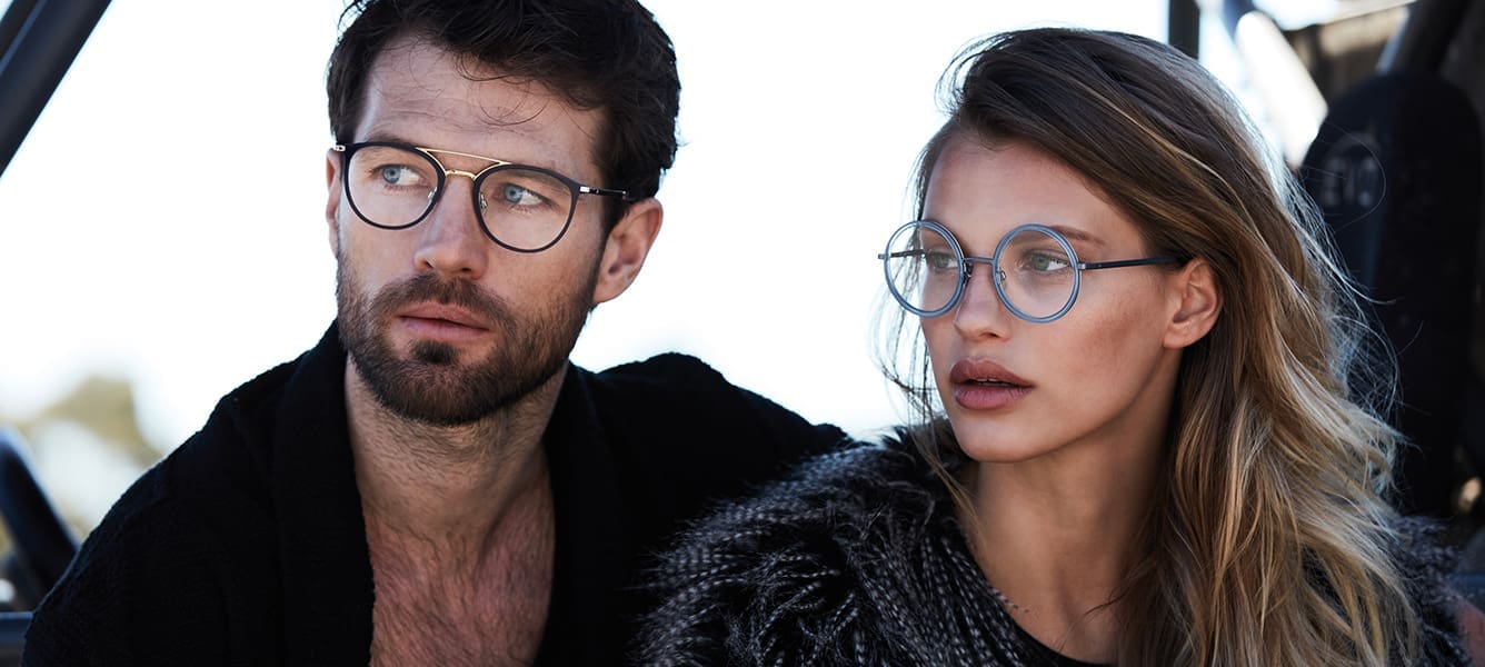 Dark haired man wearing black wire frame with woman with long brown hair wearing blue round wire frame with eyeglasses Maple Grove Eye Doctors