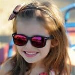 girl-wearing-red-mirrored-sunglasses Little girl with long brown hair wearing red mirrored sunglasses in a black frame from Maple Grove Eye Doctors