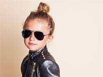 Young girl with a bun in her hair wearing aviator sunglasses with dark lenses from Maple Grove Eye Doctors at Pearle Vision