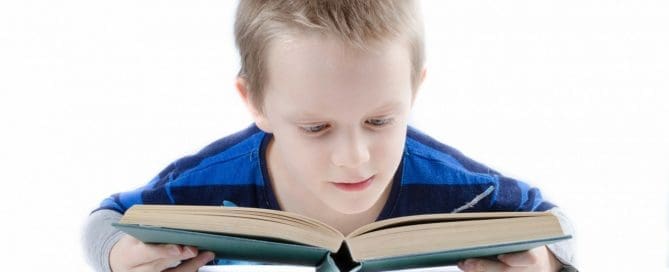 Boy holding Book close to read Maple Grove Eye Doctors at Pearle Vision
