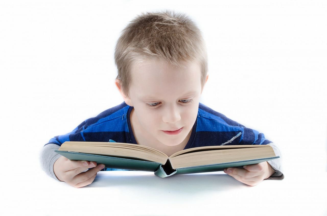 Boy holding Book close to read Maple Grove Eye Doctors at Pearle Vision