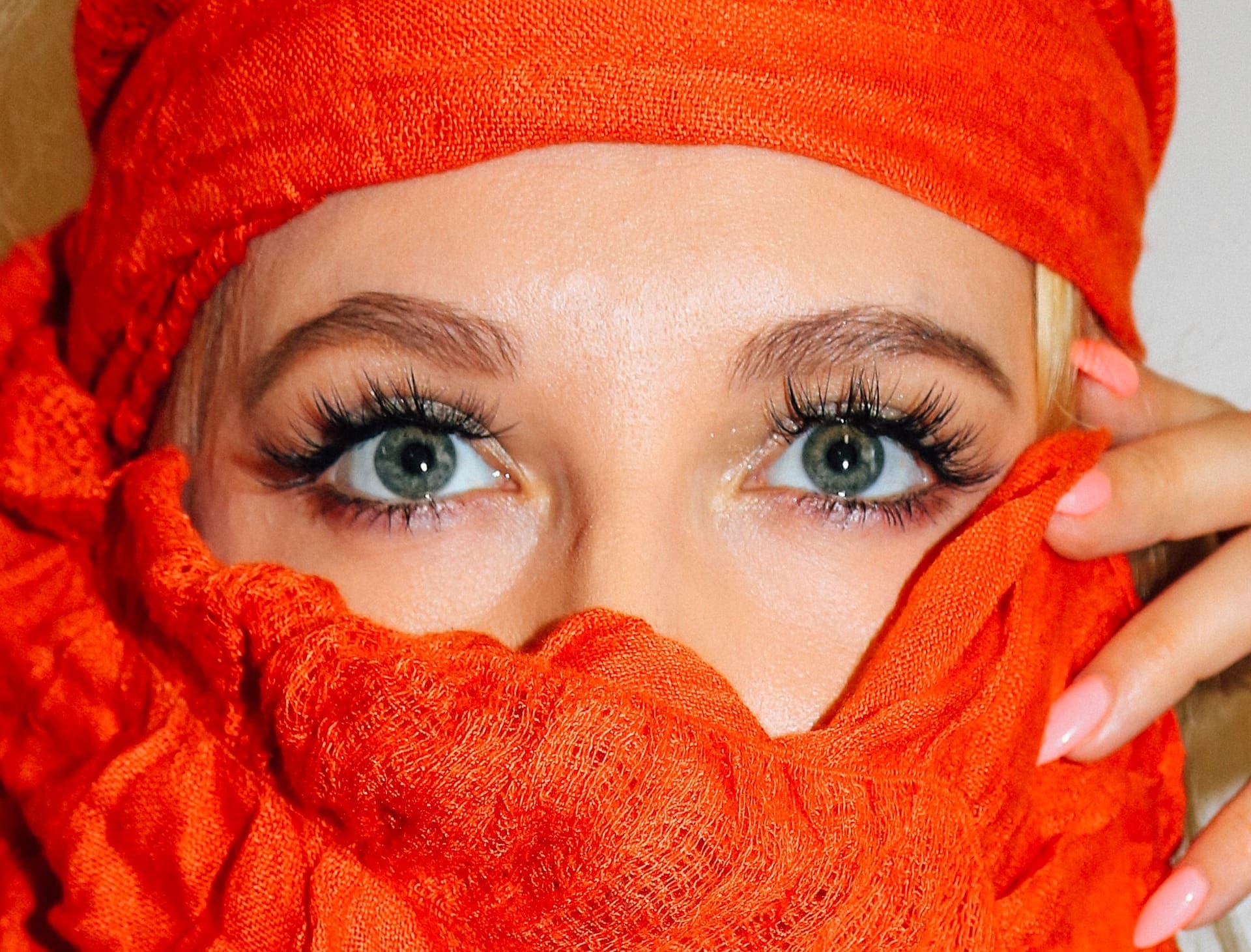 Woman in orange scarf wearing Eye lash extensions Maple Grove Eye Doctors at Pearle Vision