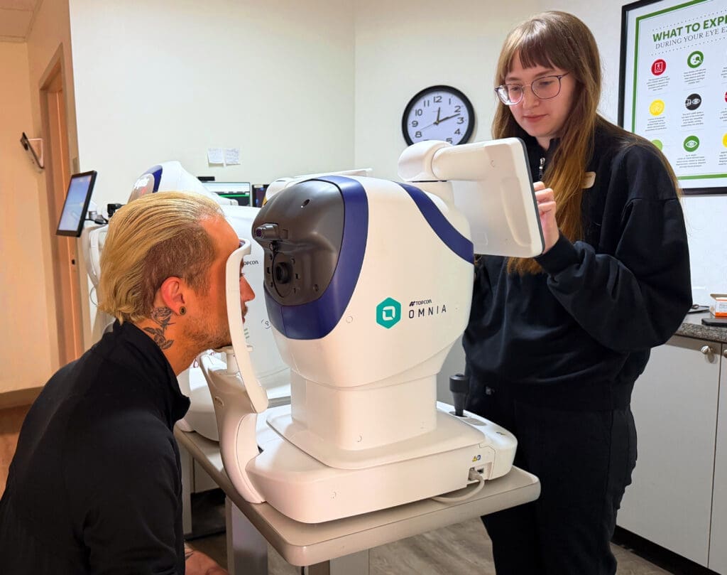 Optometric technician operating a Topcon advanced retinal imaging system during an eye exam at Maple Grove Eye Doctors