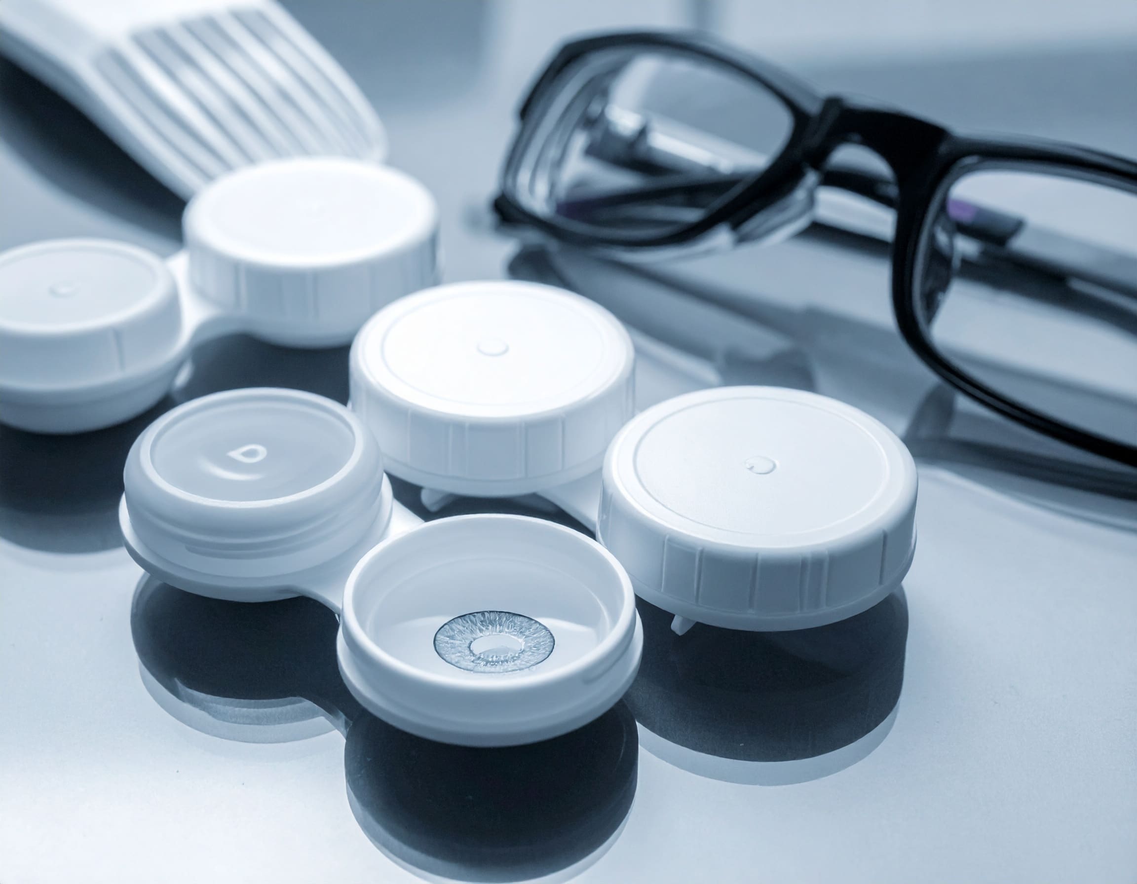 Multifocal contact lens in case beside a pair of eyeglasses from Maple Grove Eye Doctors at Pearle Vision